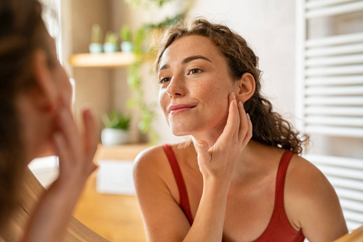 Woman checking face for stubborn acne with clear skin